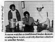 A nurse watches a traditional healer demonstrating how to mix oral rehydration solution to another healer.